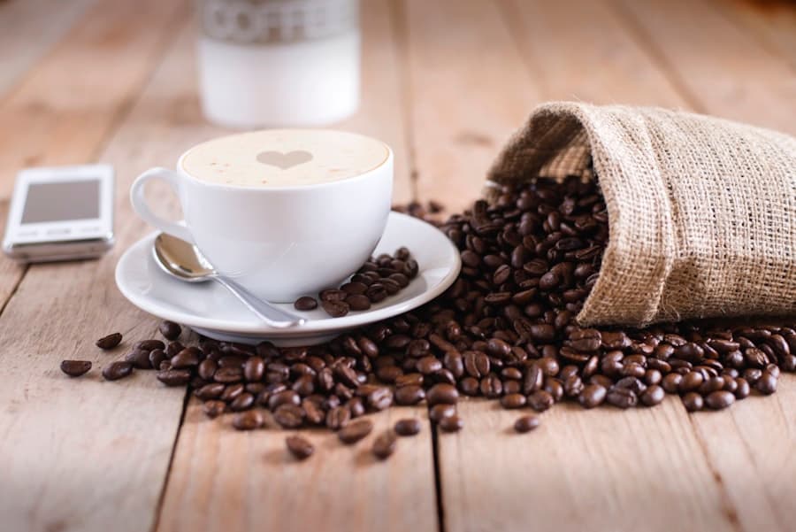 Cappuccino servi sur une table en bois, entouré de grains de café