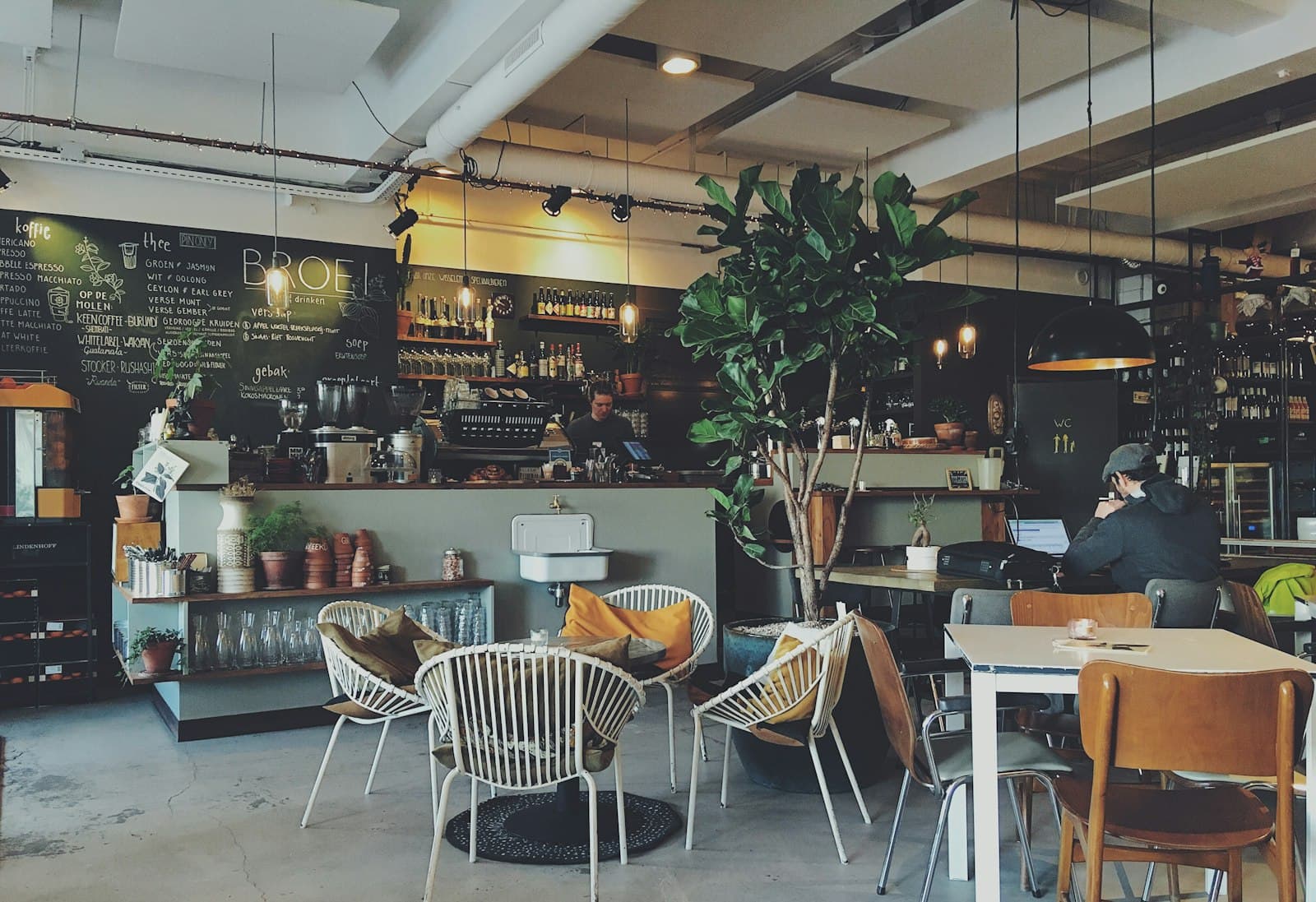 Tables et fauteuils en rotin devant le bar et son ardoise