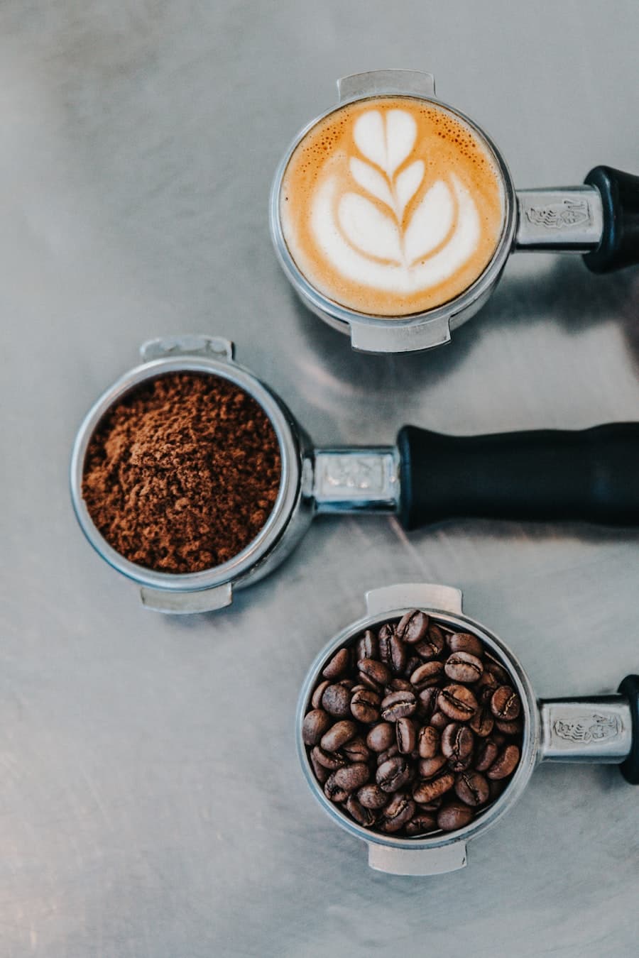 Trois porte-filtres alignés : latte art, mouture fraîche et grains entiers