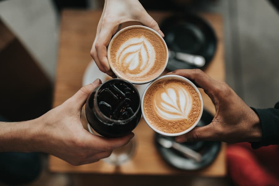 Trois personnes trinquant avec leurs cafés au-dessus d'une table en bois