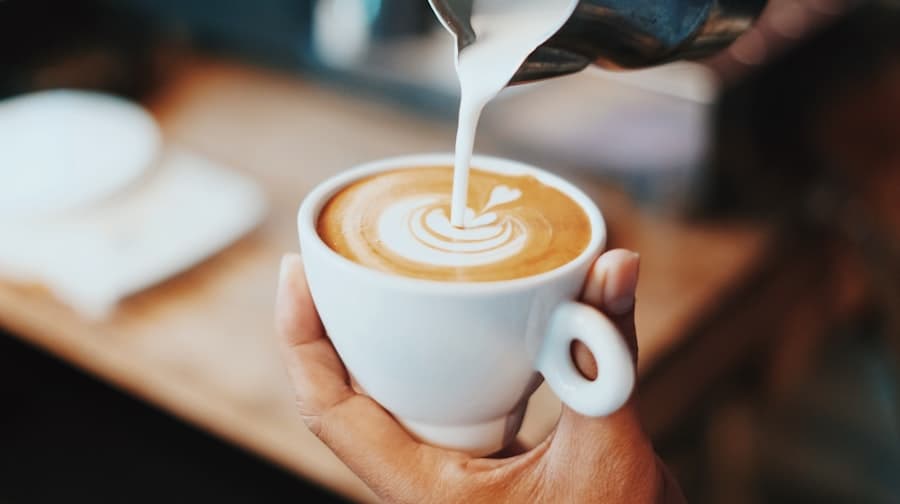 Versement du lait micro-moussé dessinant un cœur dans la tasse